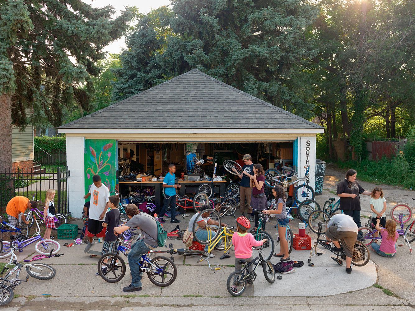 Kyle supervises over a group of children who perform maintenance and build bikes for themselves. He is part of the Urban Neighborhood Initiatives Program (http://unidetroit.org), an organization dedicated to building vital neighborhoods. If the children volunteer 20 hours at UNI they can receive a bike for free from Kyle. Children Working on Their Bicycles at Southwest Riders, Southwest Side, Detroit 2013