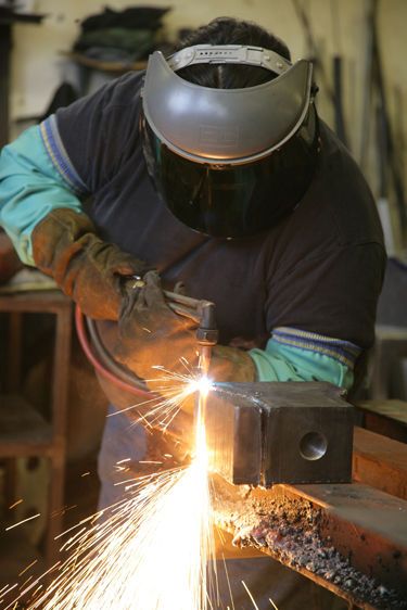Iron worker cutting steel blocks for roof trusses, Eastern Market