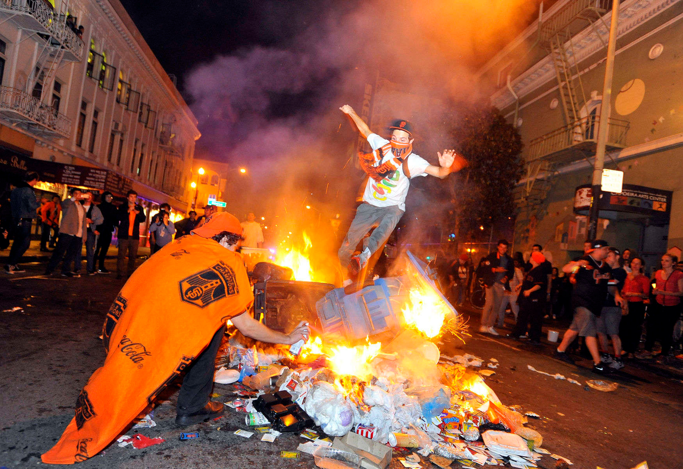 WORLD SERIES REACTIONS: A man jumps over burning trash while vandalism ensues after the Giants beat the Royals in the 2014 World Series in San Francisco.