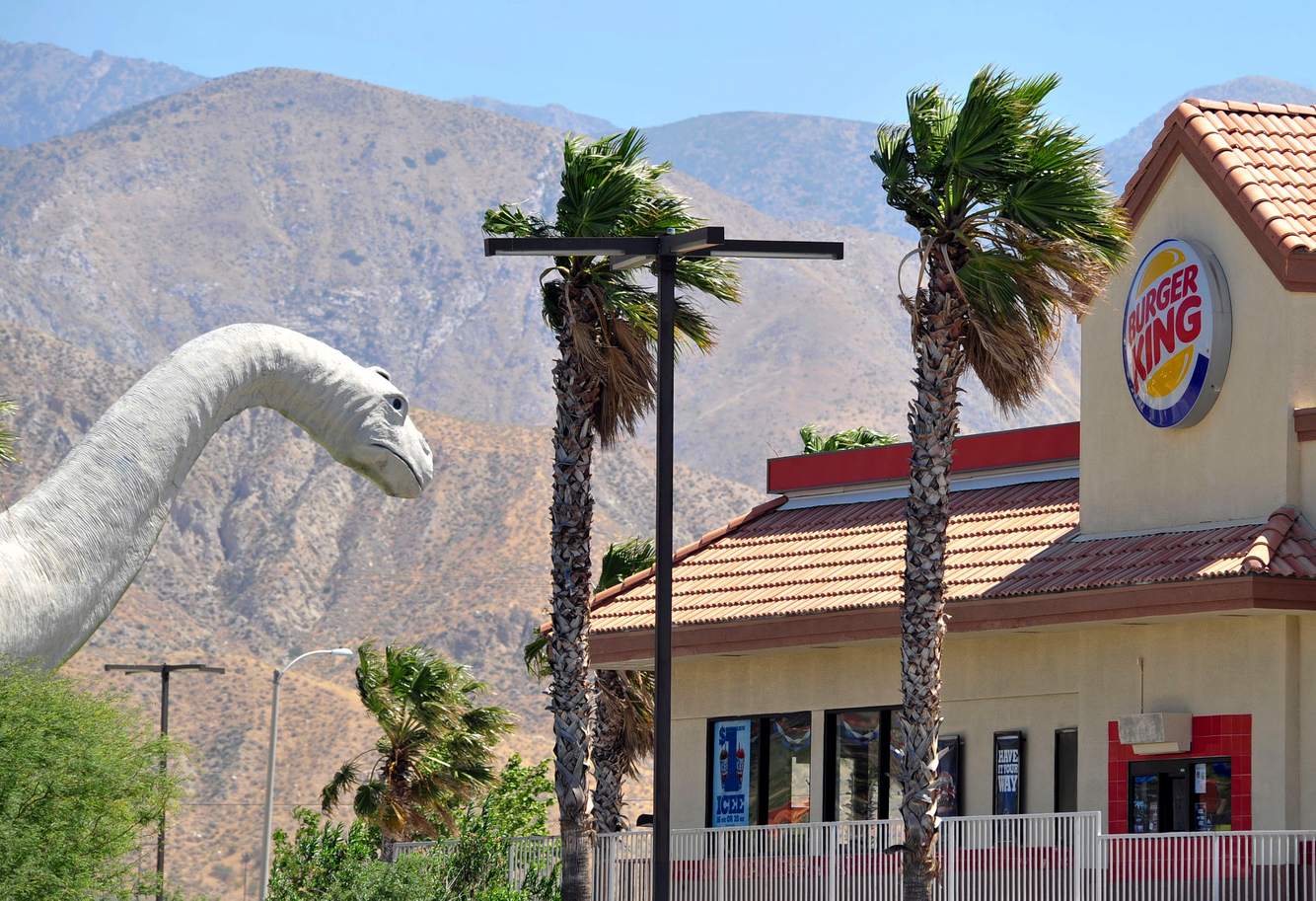 A dinosaur statue is seen near a Burger King in Palm Desert, California.