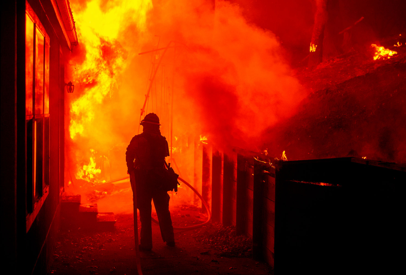A firefighter attempts to save a burning home during the Valley fire.