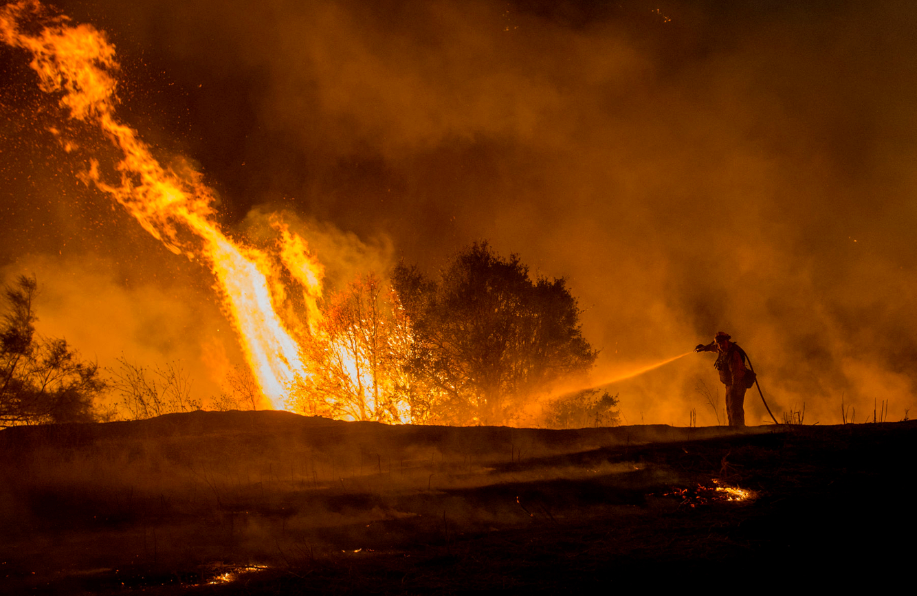 A lone firefighter douses impending flames