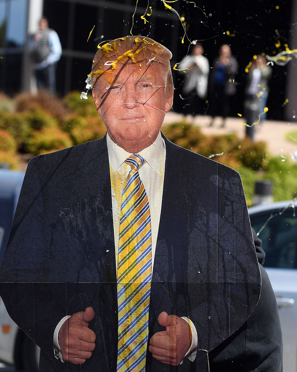 An egg is thrown at a cardboard cutout of Donald Trump during a protest where he was speaking in San Francisco.
