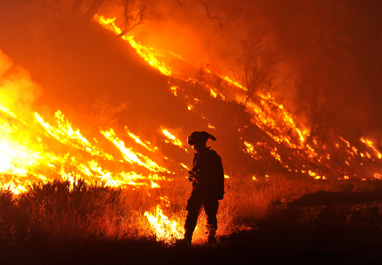 A firefighter pauses while surrounded by flames