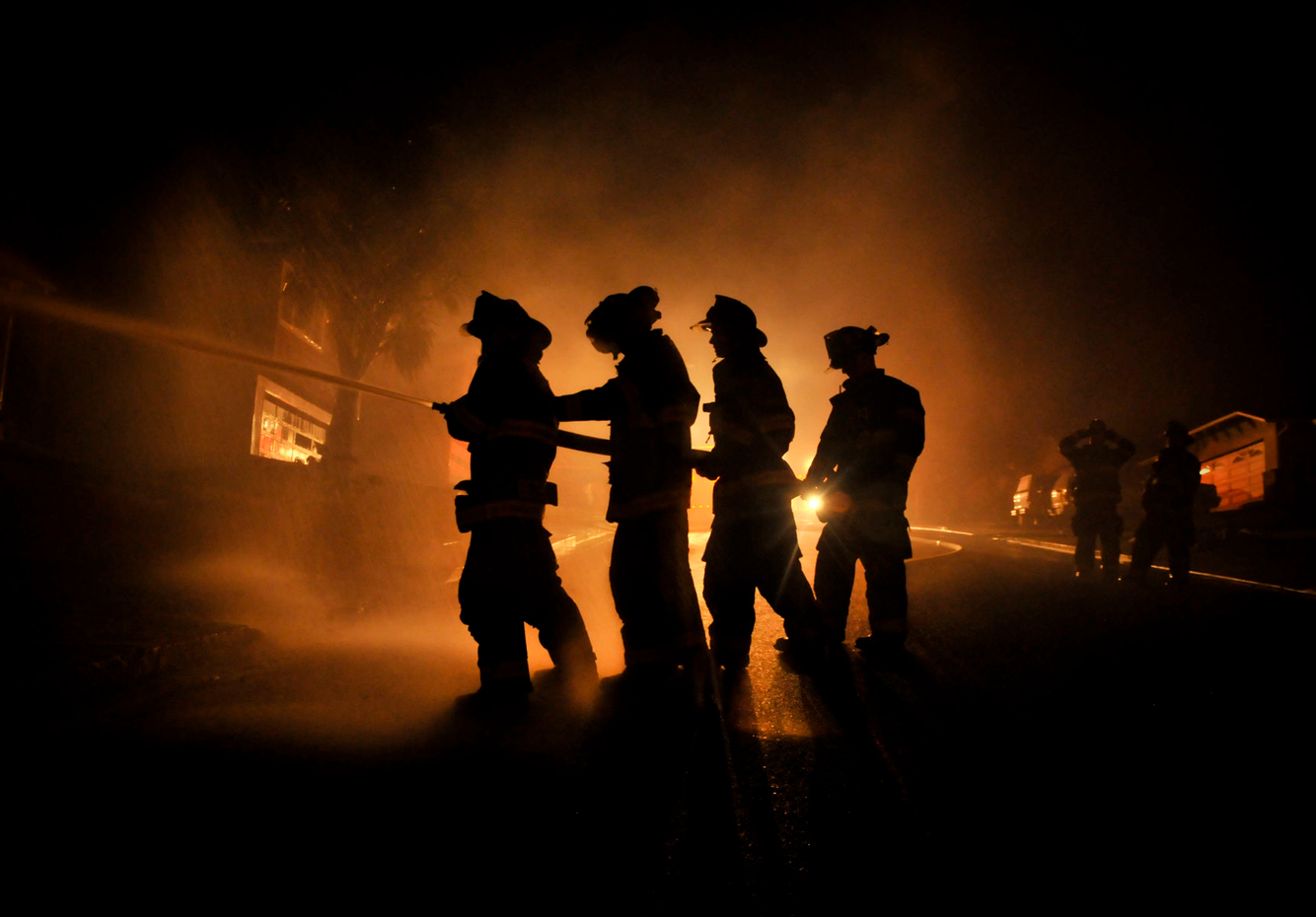 Firefighters aim a hose towards a burning house after a gas explosion