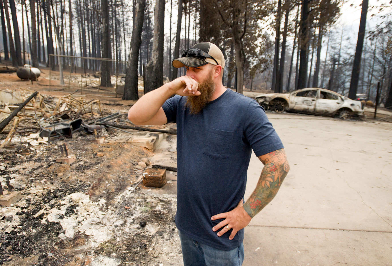 Josh Wood reacts while viewing the burned out remains of his home.