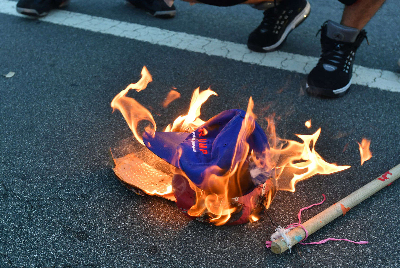 Protesters burn a Trump hat during a protest.