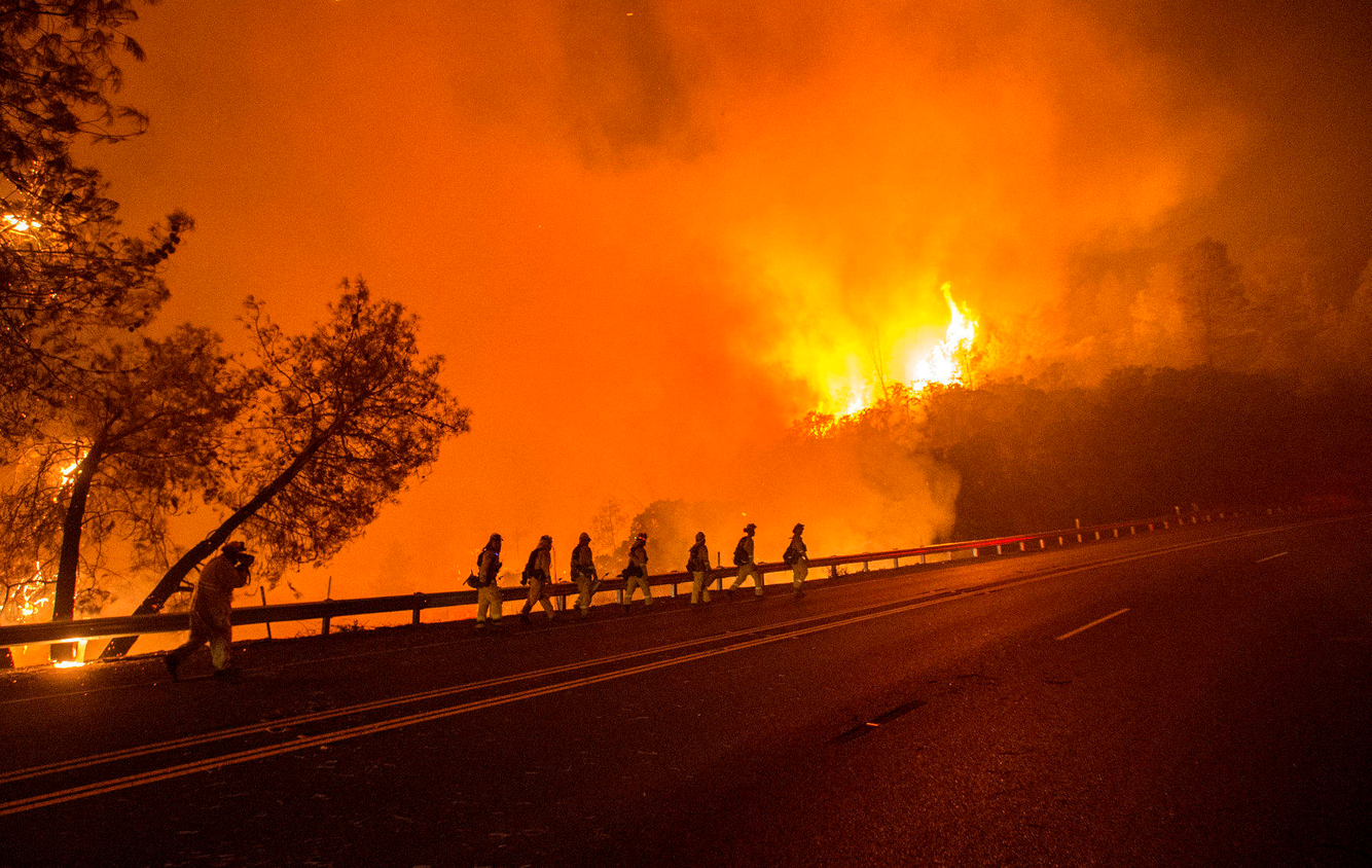 A crew of firefighters walk towards a burning hillside