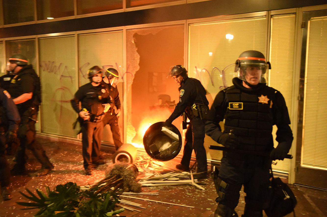 Police investigate a building firebombed during an anti-Trump protest.
