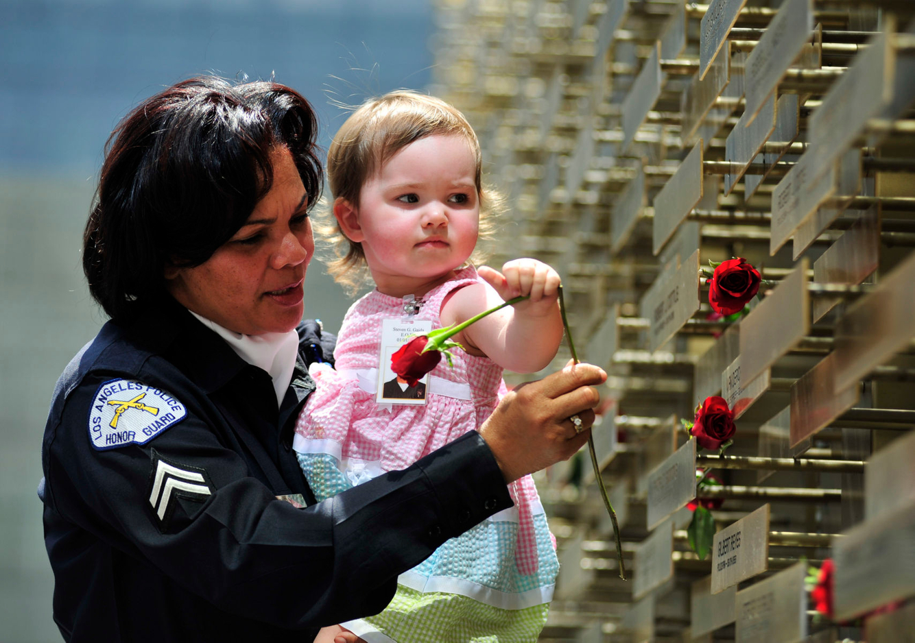 MEMORIAL: A member of th LAPD helps the niece of a fallen Officer place a rose at a memorial in Los Angeles