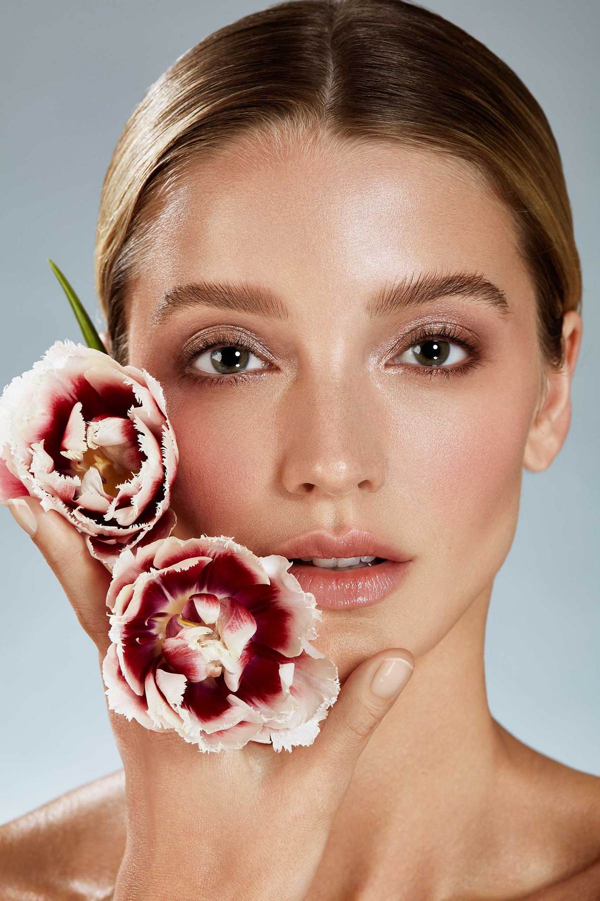 FEMALE HOLDING TULIPS NEXT TO HER FACEg