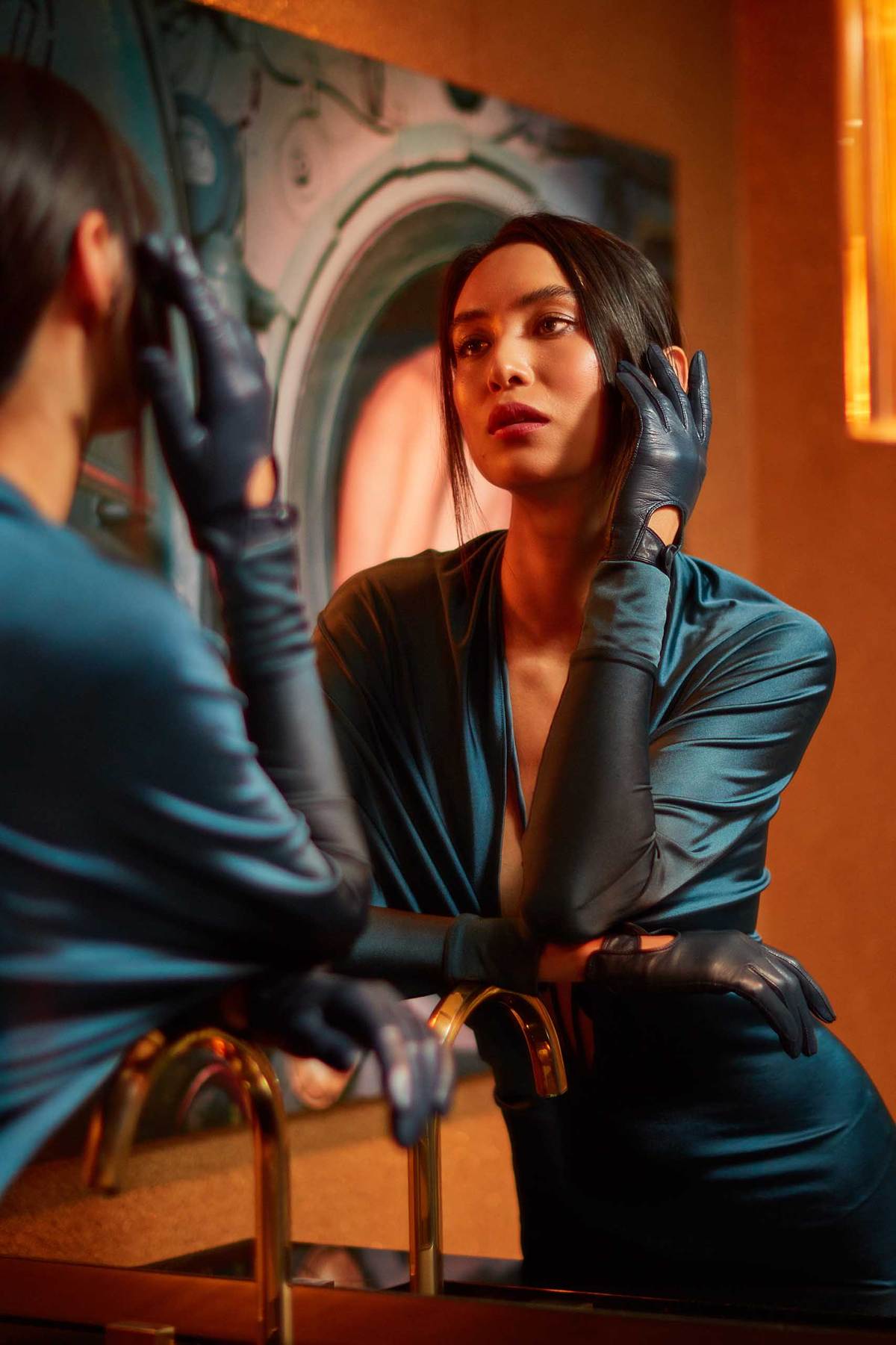 Asian model looking into the bathroom mirror wearing leathergloves