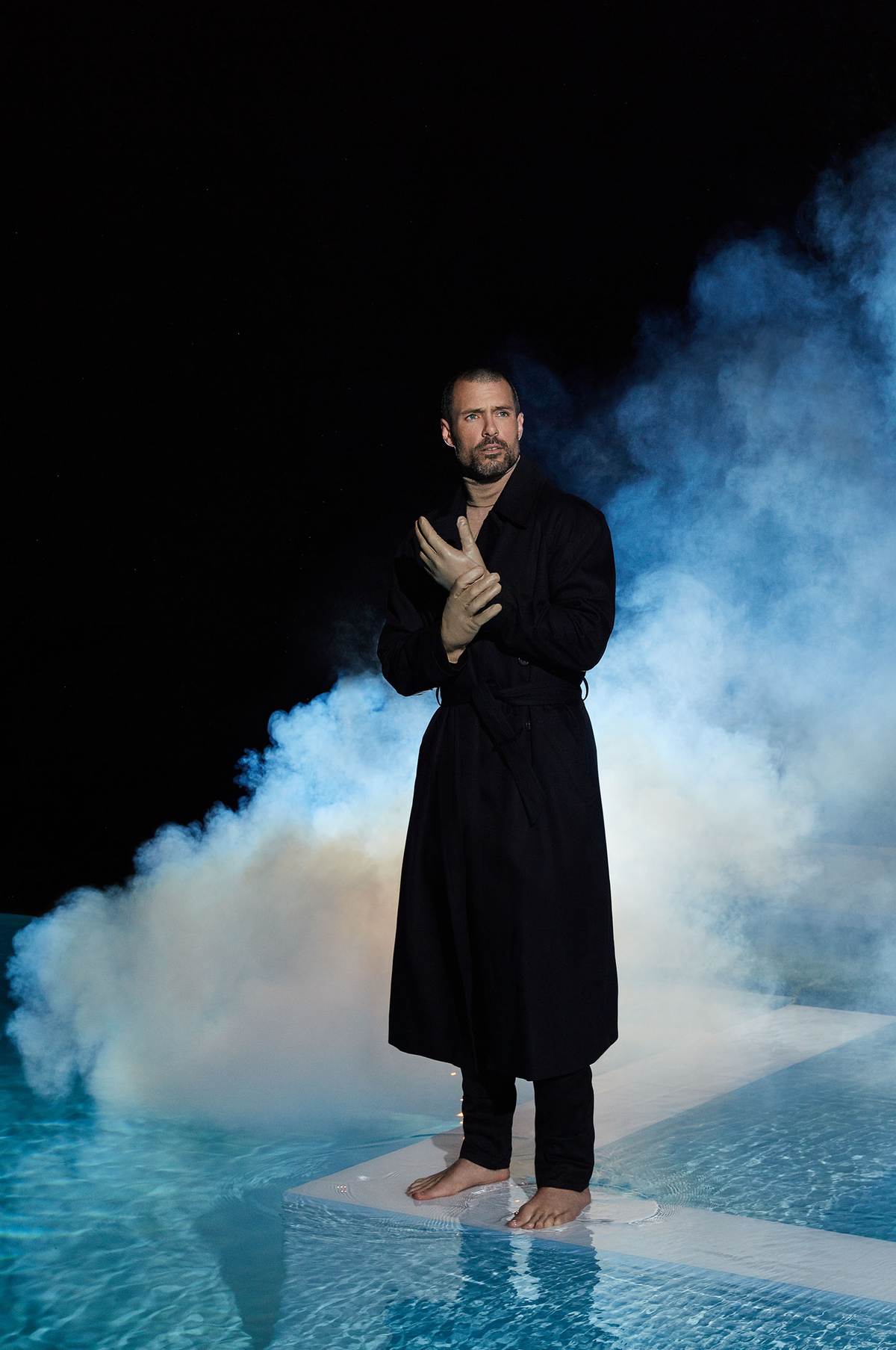 MALE wearing gloves and standing in a pool with smoke behind him