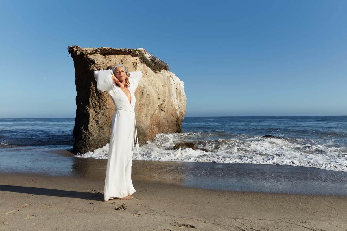 A mature woman in an embracing pose by the beach