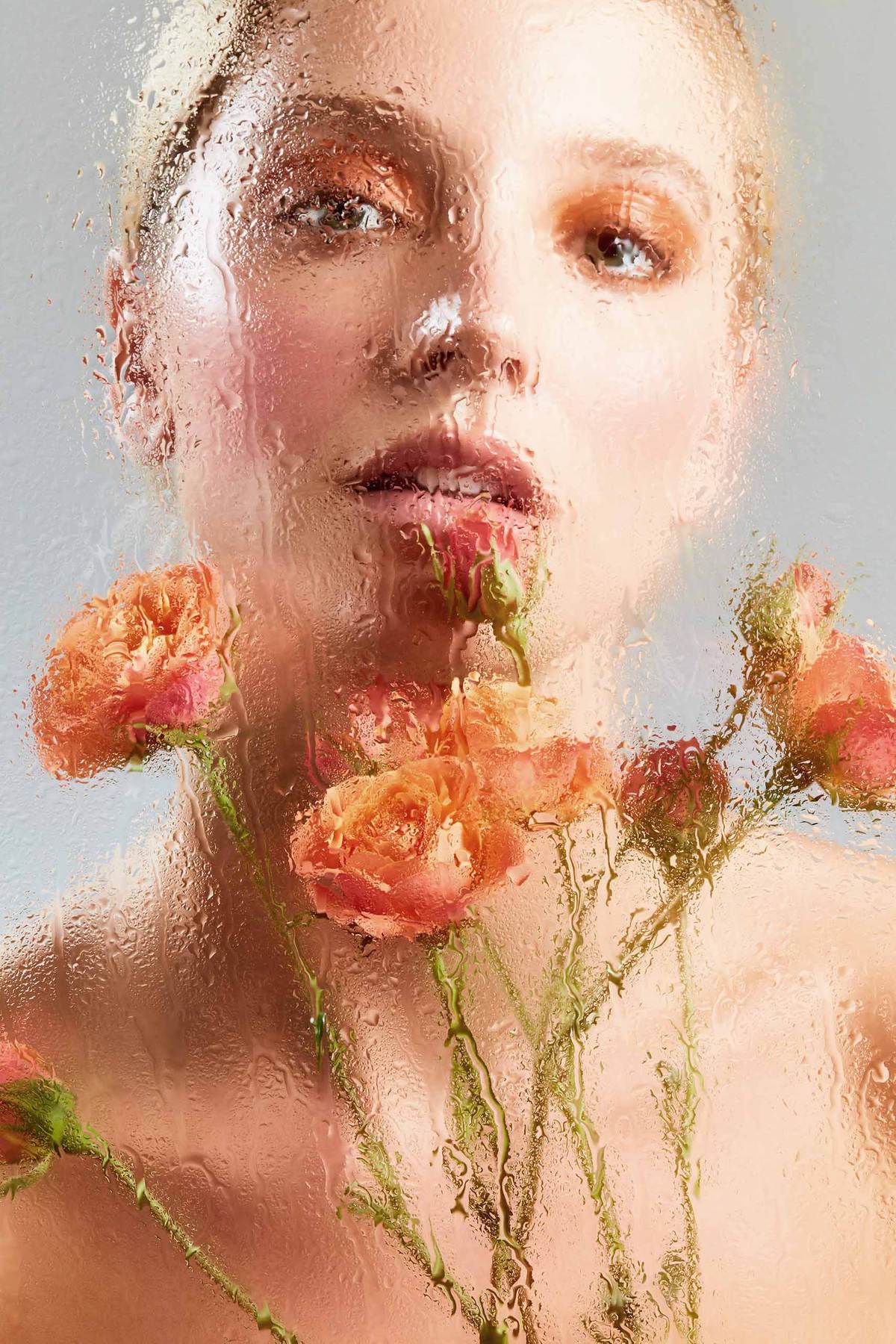 female with roses  behind a glass of water drops