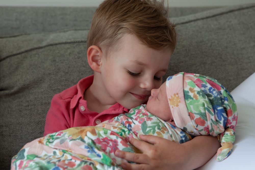 Brother holds Newborn Sister Day 5