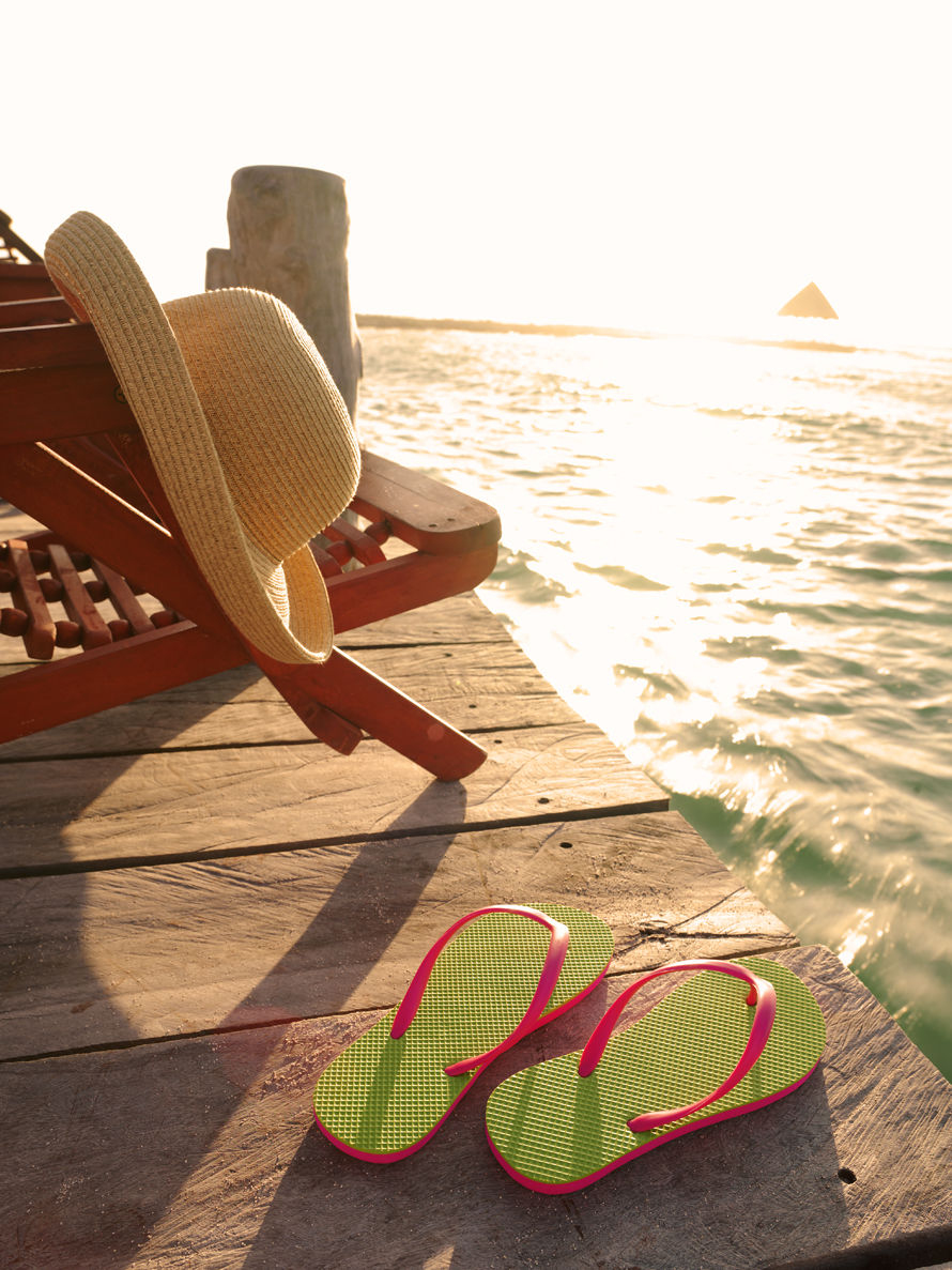 Quintana Roo, Yucatan Peninsula, Mayan Riviera, Mexico. Getty Images #200557627-001 Beach and pair of flip flops and deck chair with hat on pier
