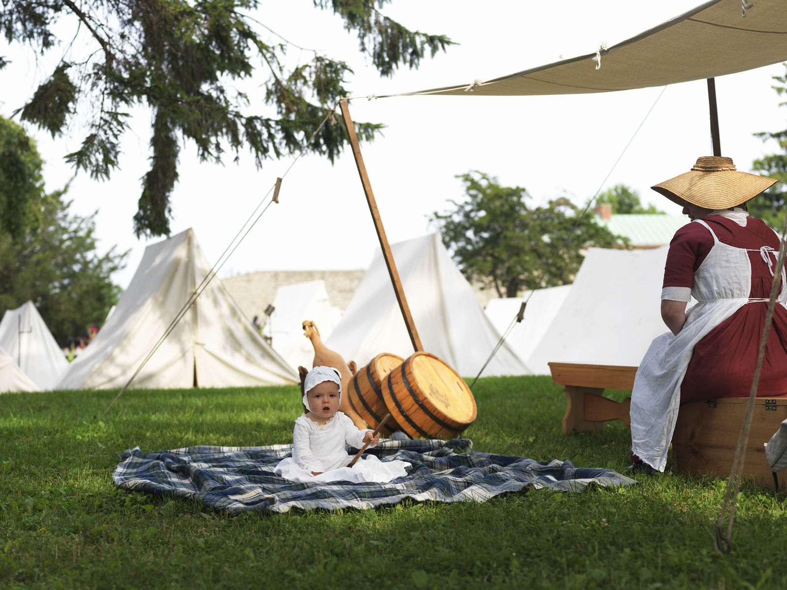 Canada, Ontario, Fort Erie, Old Fort Erie, 1812 re-enactors in period costume, baby on blanket with tents in background 1war_of_1812_27251