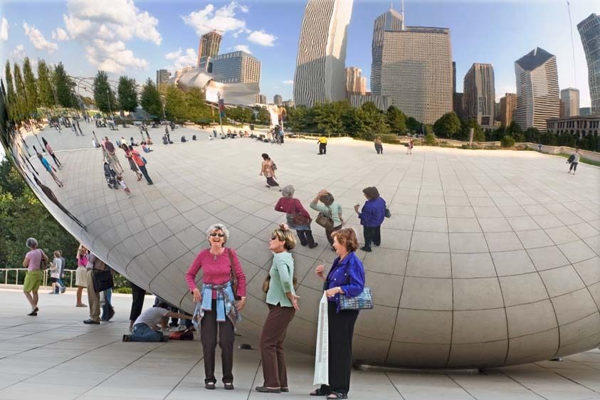 Three mature females pose in comical poses at mirror sculpture in Millenium Park in Chicago, Illinois Three senior women play