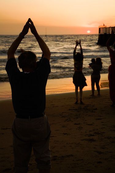Dance exercise class with seniors of men and women exercise at winter solstice on Playa del Rey beach in Los Angeles county Silhouettes of man and woman in dance class at sunset on beach
