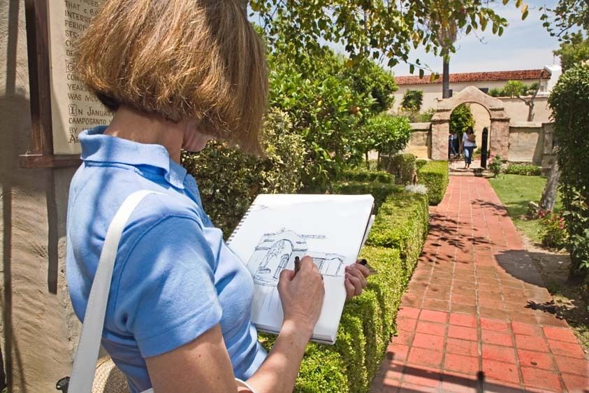 Female adult student sketches gate at San Gabriel Mission for cl