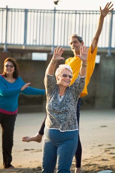 Two Mature females and one male laugh and exercise with joy on sandy Playa del Rey Beach inLos Angeles, California Senior Women and man moving in exercise on beach