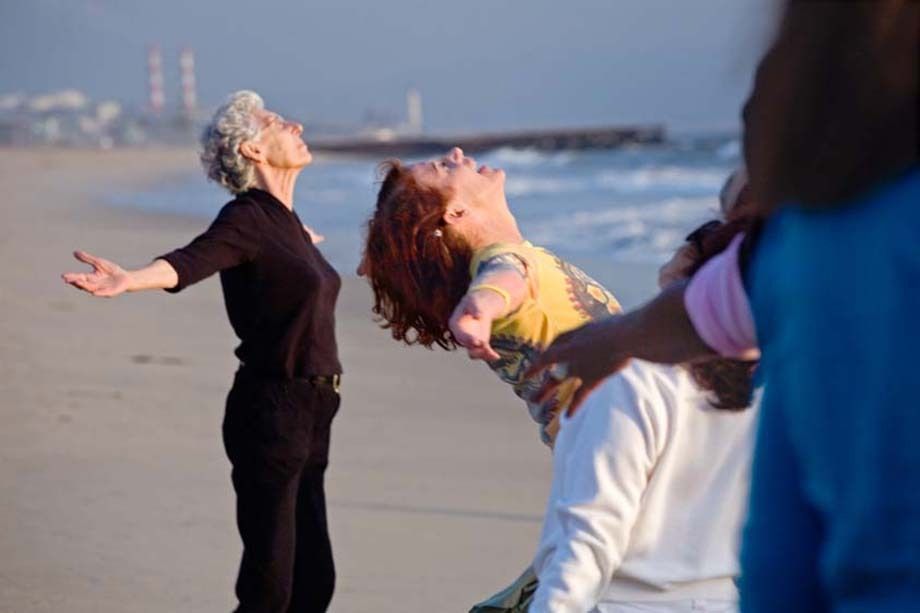 Senior females stretch out their arms in movement and exercise class on sandy Playa del Rey beach in Los Angeles, California Senior women hold out arms exercising on beach