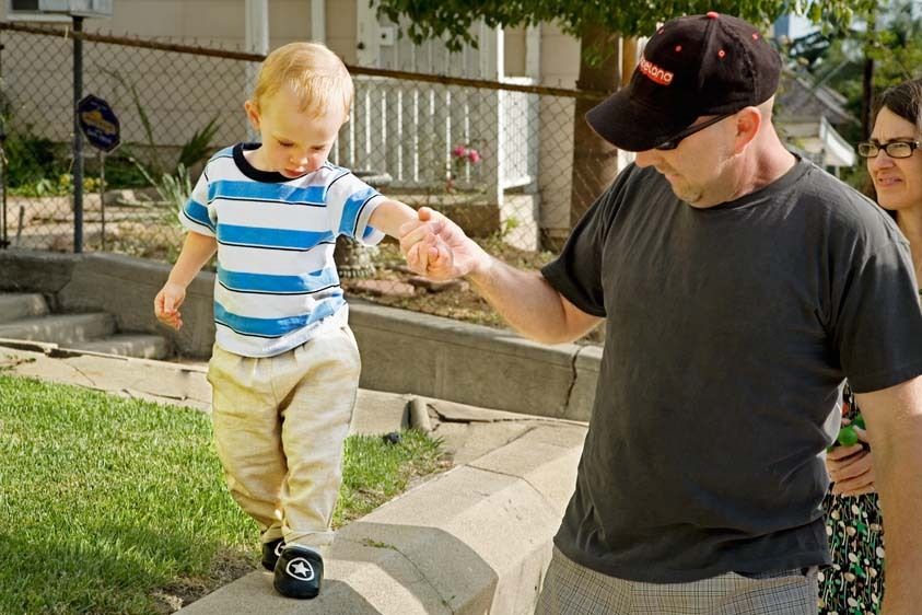 Toddler boy holds hand of father and walks on walk