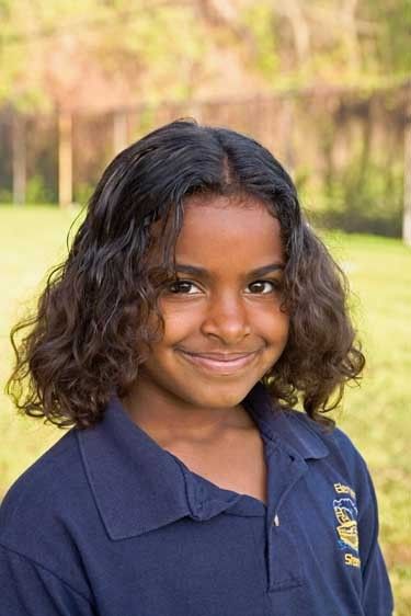 Portrait of smiling seven year old mixed ethnicity black female in school uniform outdoors Mixed ethnicity black seven year old girl portrait