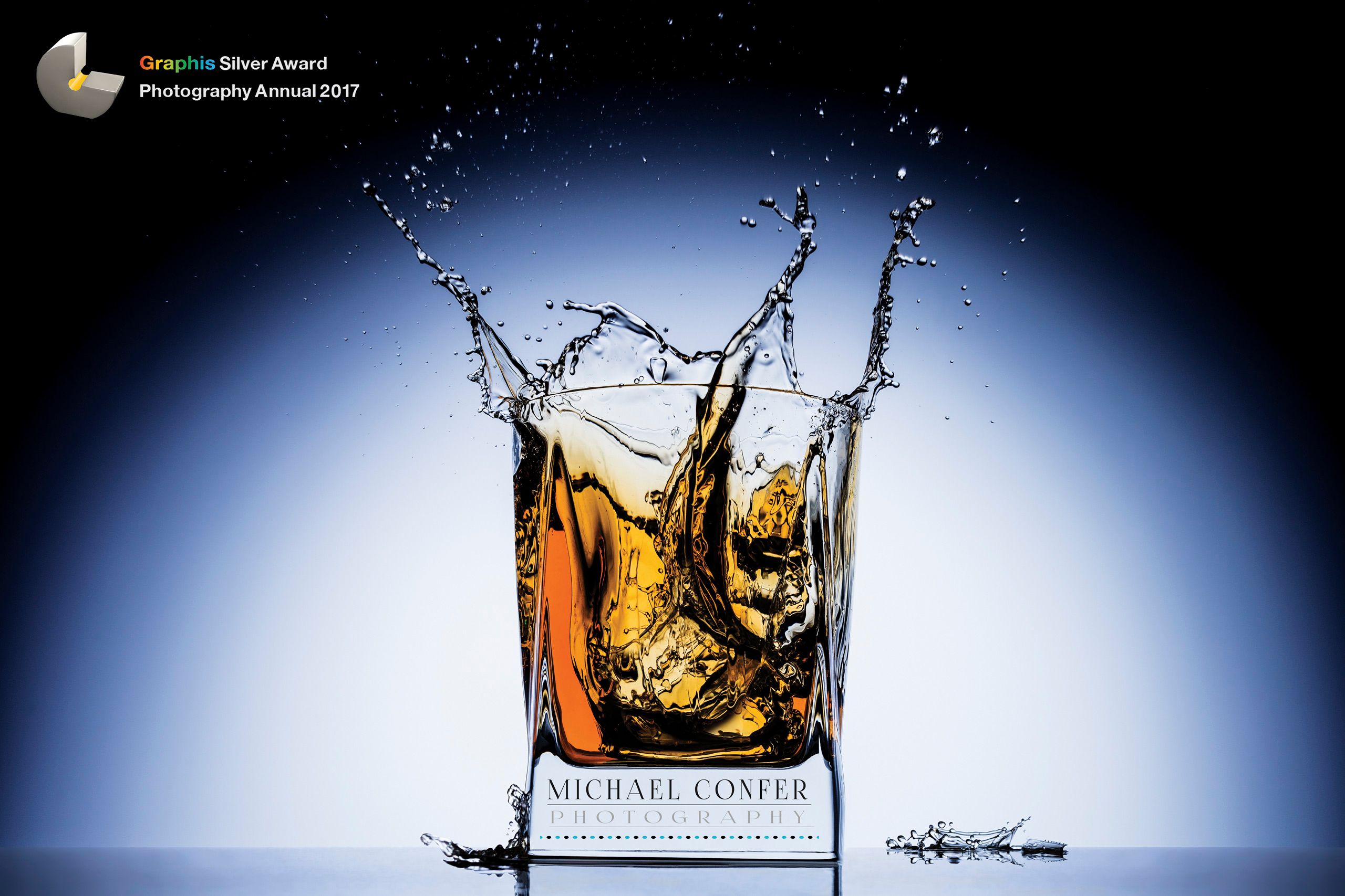 A energetic frozen splash photograph of a double old fashioned on the rocks. Graphis Photo Annual