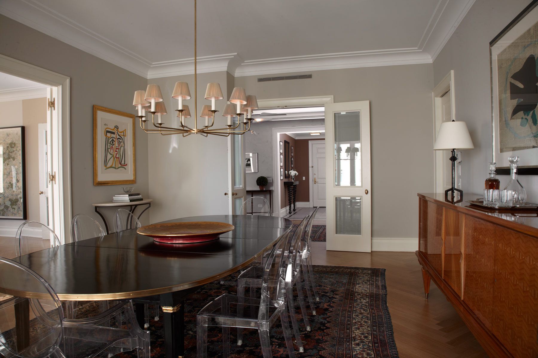 Belsey & Mahla Architects provided architectural and interior design services for this apartment renovation in New York City's newest landmark.The grand living room with dramatic park views has wide stripes on the walls, rich wool draperies on reeded brass rods, and six matching custom bronze coffee tables. A map of Haussmann's Plan for Paris, once in the Louvre's collection, occupies one wall. French aspen paneling and a ribbed oval plaster dome outfit the library; the paneling conceals a secret passage to the master suite.The dining room features French factory lights aimed to illuminate the embroidered silk draperies, and a 1940's French commode with intricate marquetry. The entry vestibule floor is made of French limestone and Saint Laurent marble. A wall-mounted console rests on found metal springs rescued from an antique shop.Paired French doors with beveled glass panes and cremone bolts connect the apartment rooms. The client's collection of modern art masterworks on paper 15 Central Park West