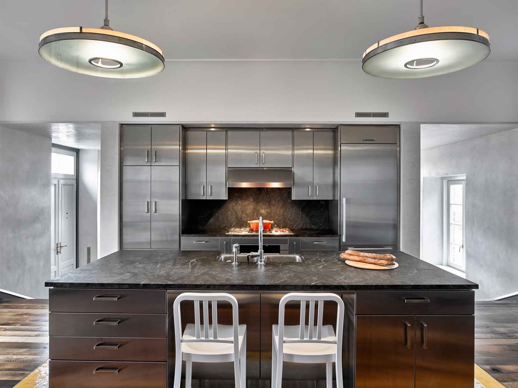 This new stone home recalls centuries -old Huguenot houses built along the Hudson River long ago, while it incorporates the latest technology and materials of the 21st century.  Fieldstone rock facing conceals insulation made from recycled blue jeans and ductwork for geothermal heating and cooling.  The 26" thick exterior walls create commodious windowsills and give a primordial sense of security.  Drawing inspiration from early American center hall plans with rooms flanking a stair on each side, this modern home departs from its Colonial cousin when it comes to light and height.  The living room ceiling soars to 14 feet, and is lit by an enormous Italian Stillnovo chandelier. The kitchen features a fireplace of epic proportions, but every modern convenience is concealed behind elegant stainless steel cabinetry.    Hudson Valley House 15.jpg