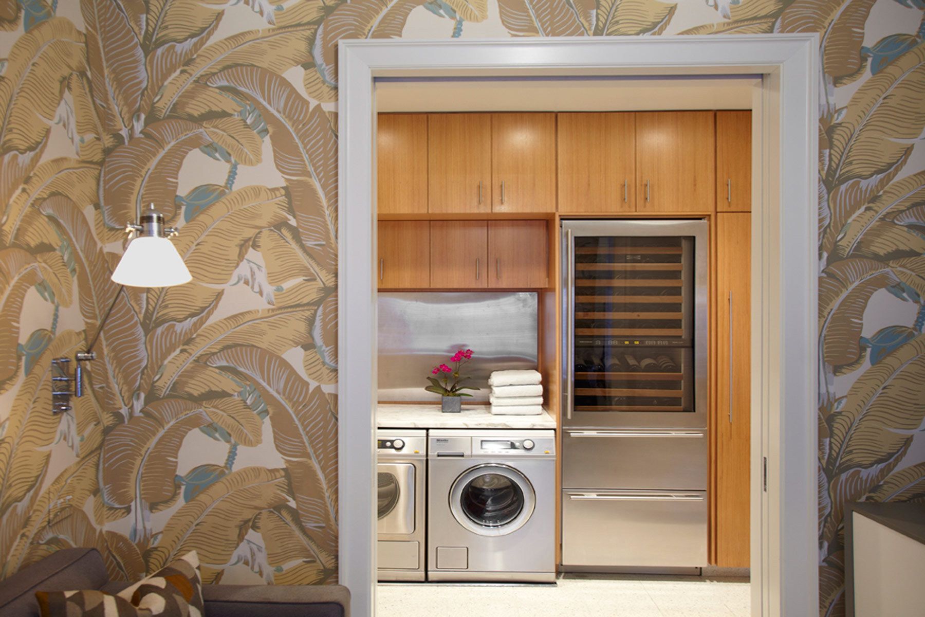 This apartment renovation features rich nut-wood veneers, walnut for the doors and pecan for the kitchen cabinetry, complemented with outsized patterned wallpaper in the entry vestibule and den.  The gallery is furnished with a Serge Mouille chandelier casting light on the silver leafed ceiling, a bronze wall-mounted BDDW vacuum tube clock, and a shagreen-fronted Roman Thomas console.Construction was completed in 2006, and Belsey & Mahla Architects continues to provide design services to the owners. West 86th Street