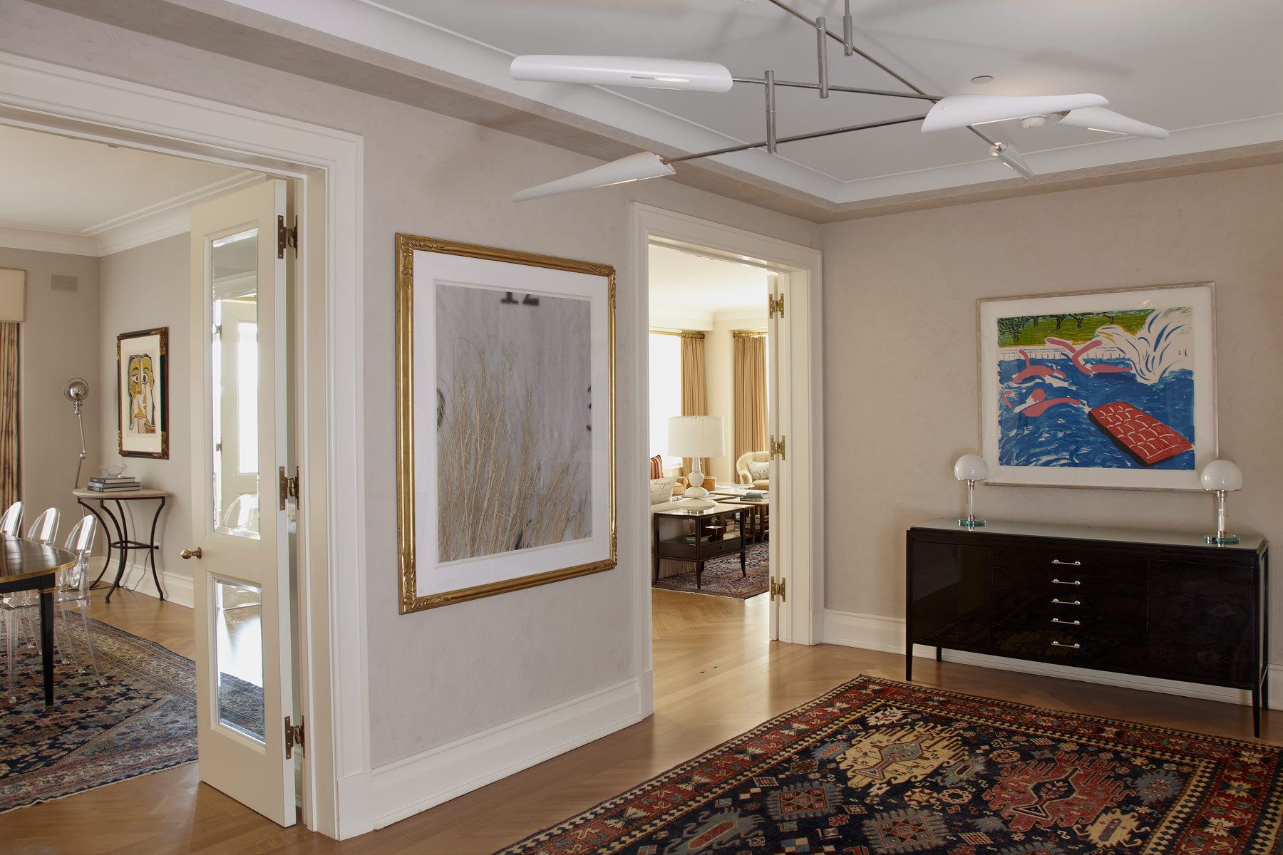 Belsey & Mahla Architects provided architectural and interior design services for this apartment renovation in New York City's newest landmark.The grand living room with dramatic park views has wide stripes on the walls, rich wool draperies on reeded brass rods, and six matching custom bronze coffee tables. A map of Haussmann's Plan for Paris, once in the Louvre's collection, occupies one wall. French aspen paneling and a ribbed oval plaster dome outfit the library; the paneling conceals a secret passage to the master suite.The dining room features French factory lights aimed to illuminate the embroidered silk draperies, and a 1940's French commode with intricate marquetry. The entry vestibule floor is made of French limestone and Saint Laurent marble. A wall-mounted console rests on found metal springs rescued from an antique shop.Paired French doors with beveled glass panes and cremone bolts connect the apartment rooms. The client's collection of modern art masterworks on paper 15 Central Park West