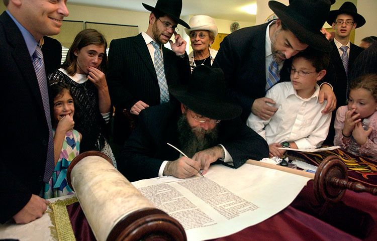 Rabbi Tzvi Chaim Pincus, center, of Brooklyn, NY, nears completion of the writing of the Torah as onlookers watch at the home of Michael Mostofsky, far left, in Norfolk, Va.  The Torah is the most important document in Judaism. 1writing_of_torah