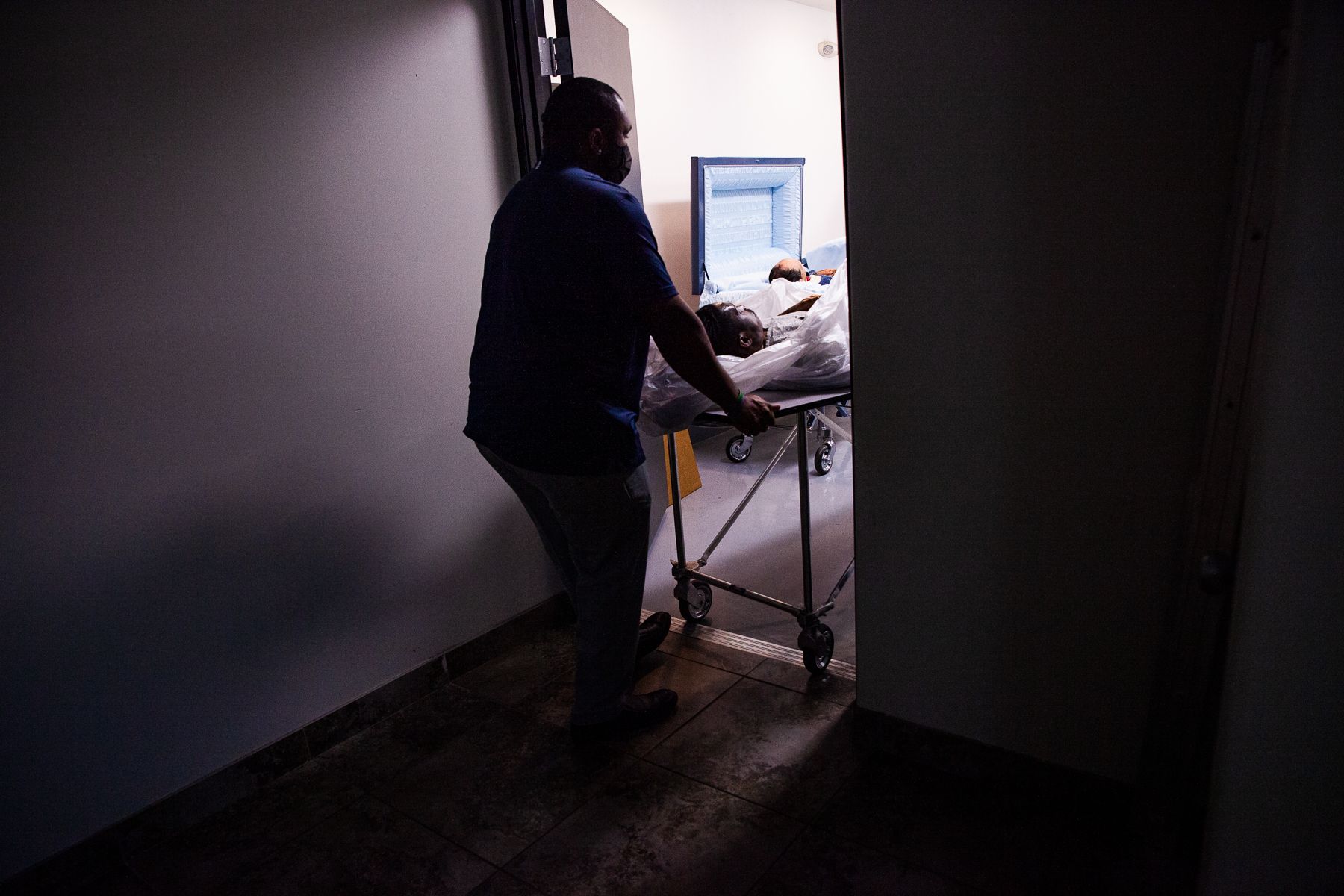 Officer manager Reginald Burgan moves a body into the hallway at Peace Chapel Funeral Home in Phoenix on March 8, 2021. 2021_0423_FinalProject_Mariani-013.jpg