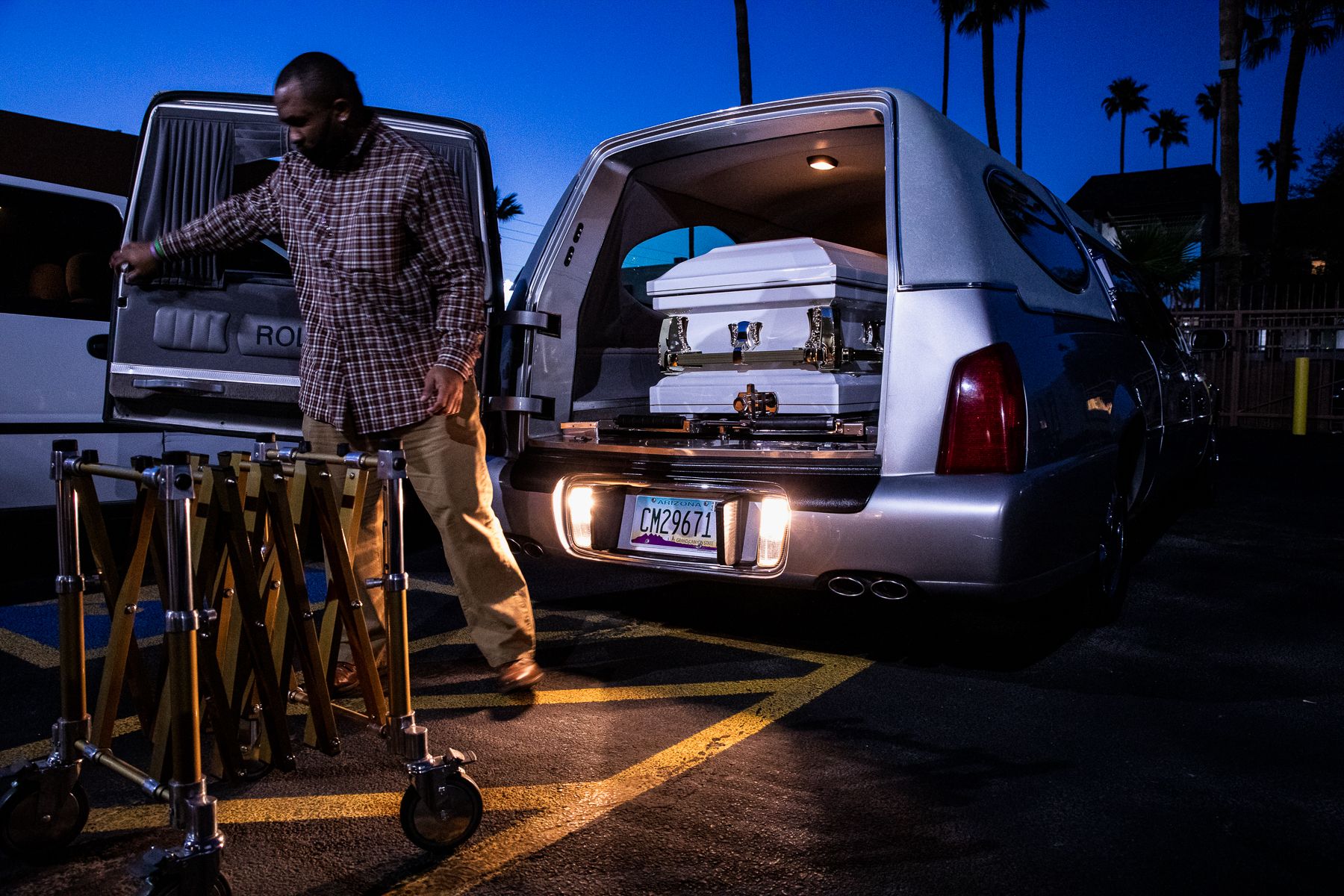 Office manager Reginald Burgan places a casket in a hearse at the end of a shift outside Peace Chapel Funeral Home in Phoenix on March 4, 2021. During the pandemic, Peace Chapel workers have pulled 14- to 16-hour shifts to keep up with demand. 2021_0423_FinalProject_Mariani-016.jpg