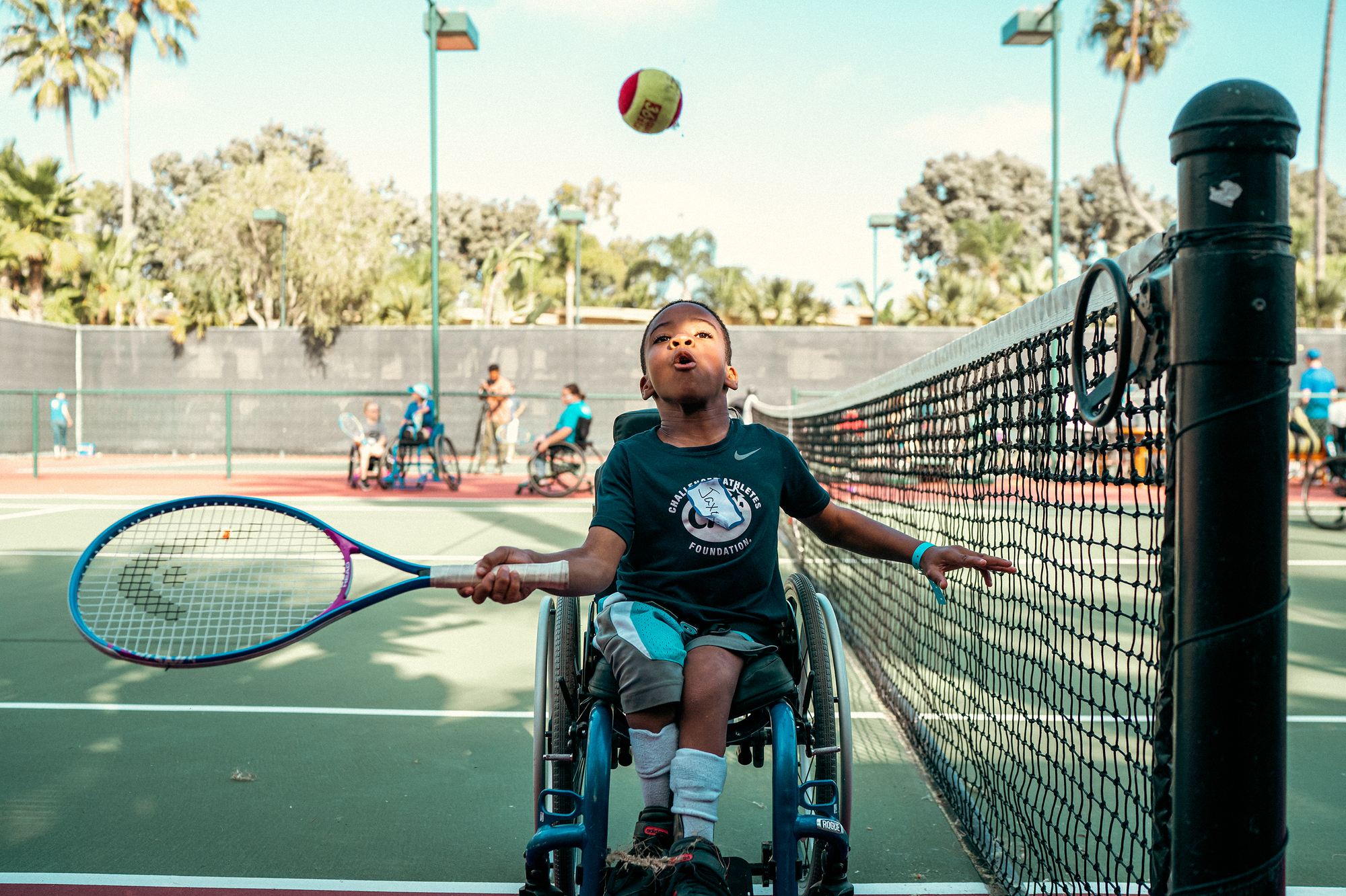 young boy in wheelchair plays tennis 