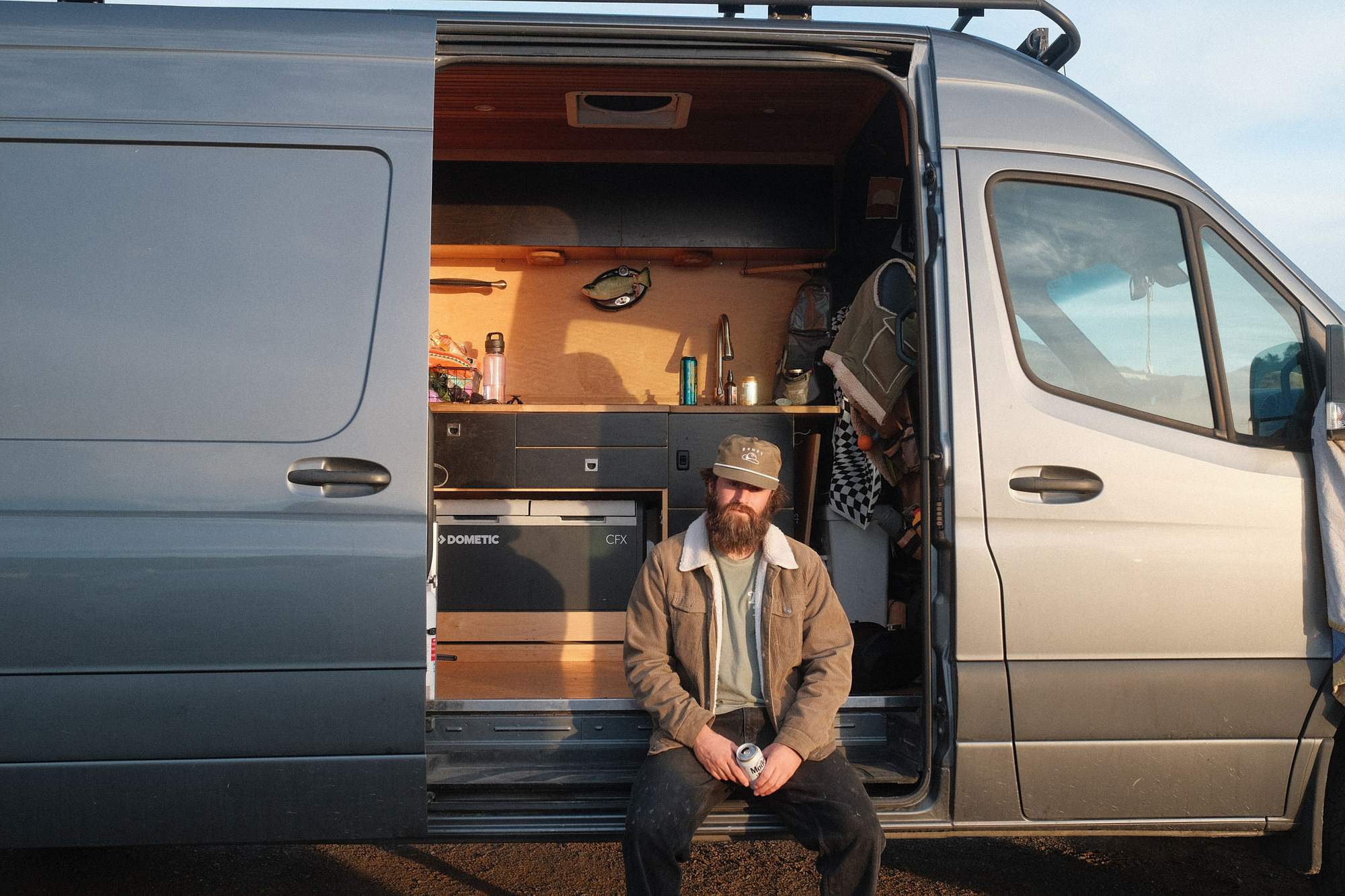 young hipster sits on the edge of his van 