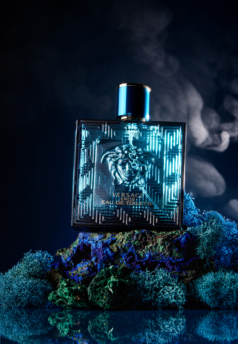 Versace Eros bottle atop blue and green props 