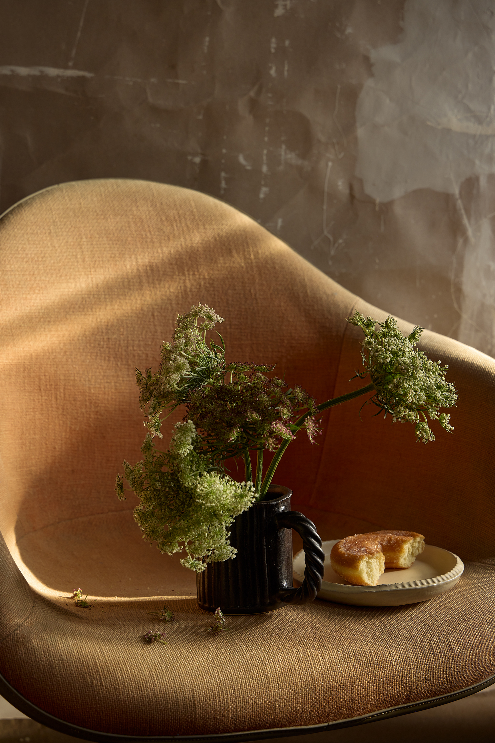 mug and plate rests on a tan chair George Barberis