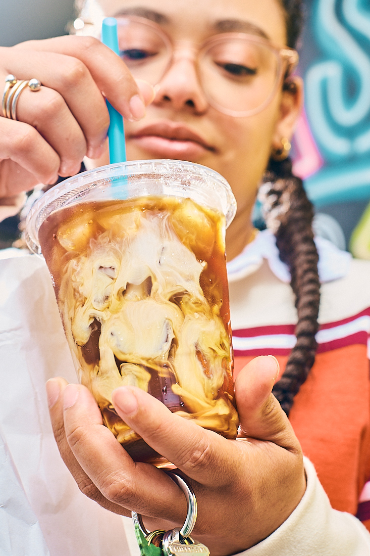 young gen z girl stirs coffee 