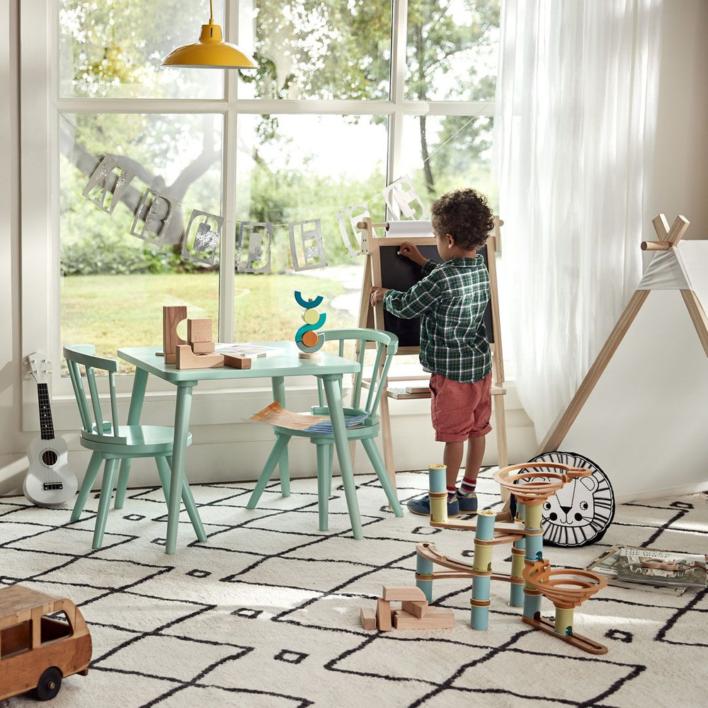 young boy in red shorts draws on a chalk board by the window of his bedroom. young boy playing with chalk board by window