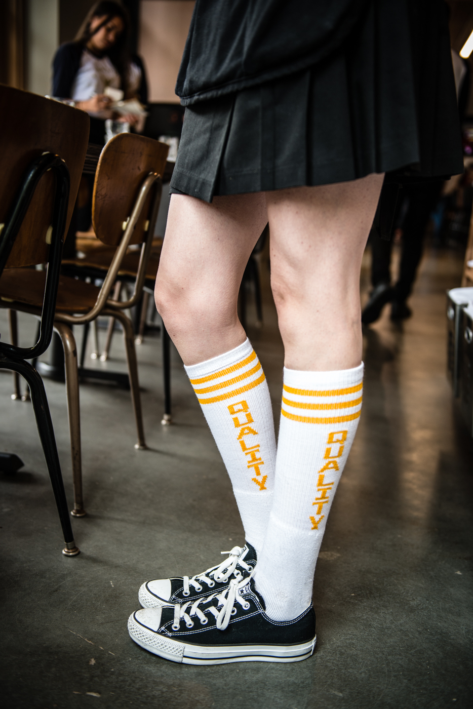 Quality socks, tube socks, fresh tennis shoes, classic look Girl standing next to Antique school room chairs