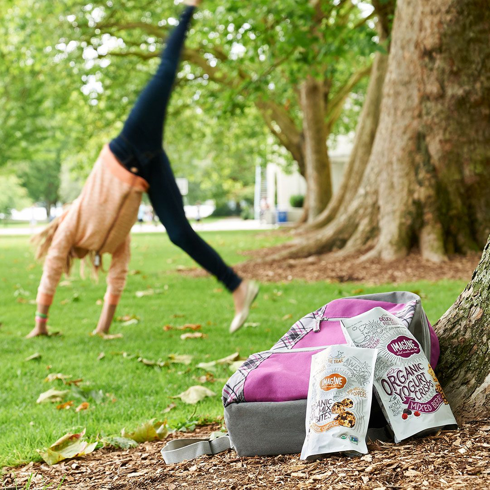 woman cartwheels in the park near her pink backpack and organic yogurt snacks. photo retouching by jon birdseye woman cartwheels in the park