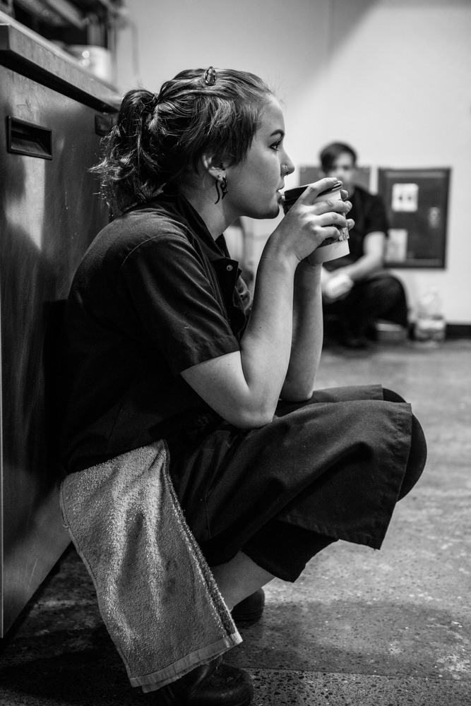 Girl kneeling behind the counter drinking cup of coffee lifestyle photography by Sarah Flotard of Sally Bjornsen Represents Girl kneeling behind the counter drinking cup of coffee lifestyle photography by Sarah Flotard of Sally Bjornsen Represents