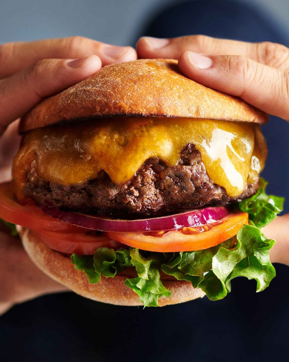 Two hands hold authentic american Tillamook cheeseburger