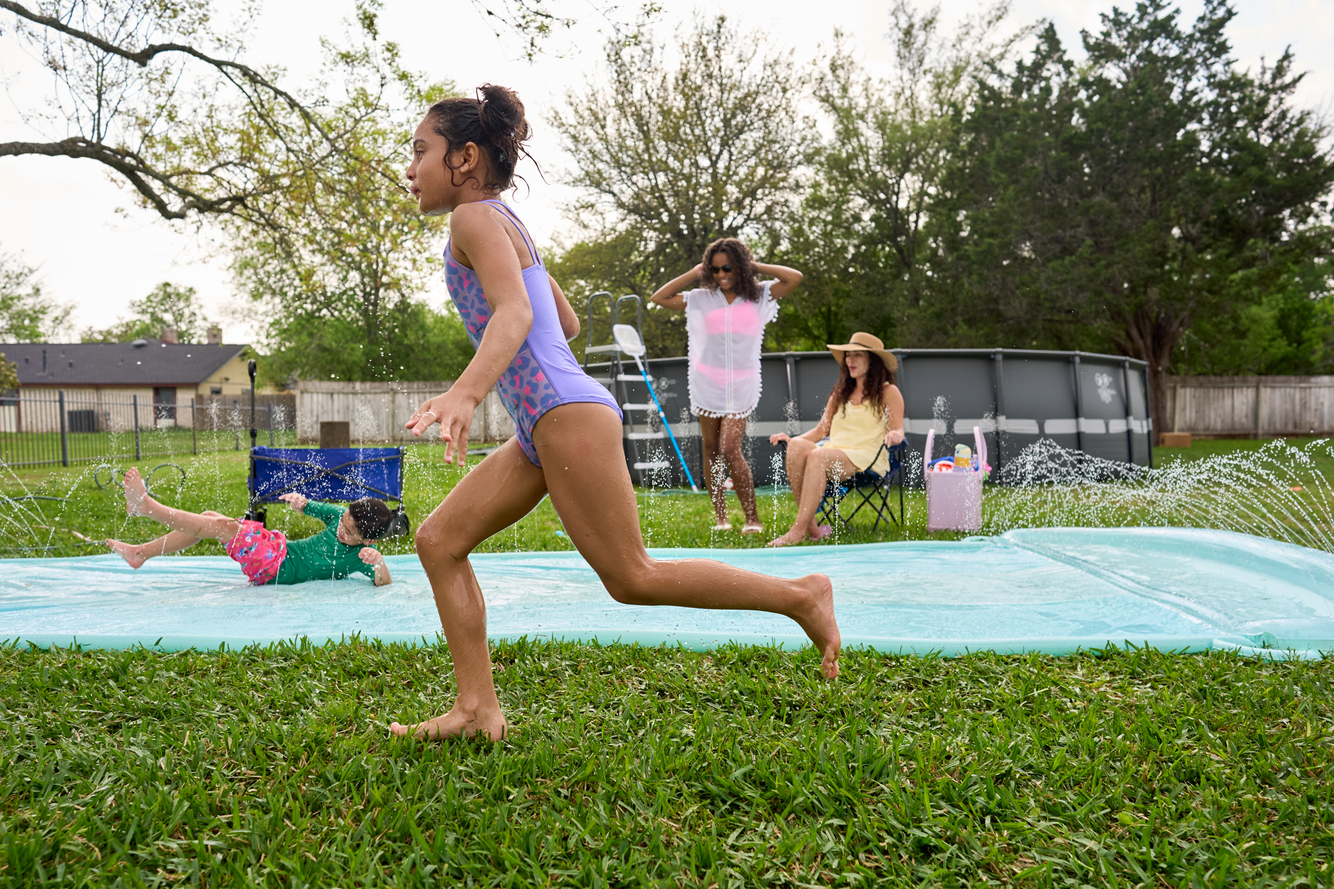 young girl runs and plays on outdoor waterslide 