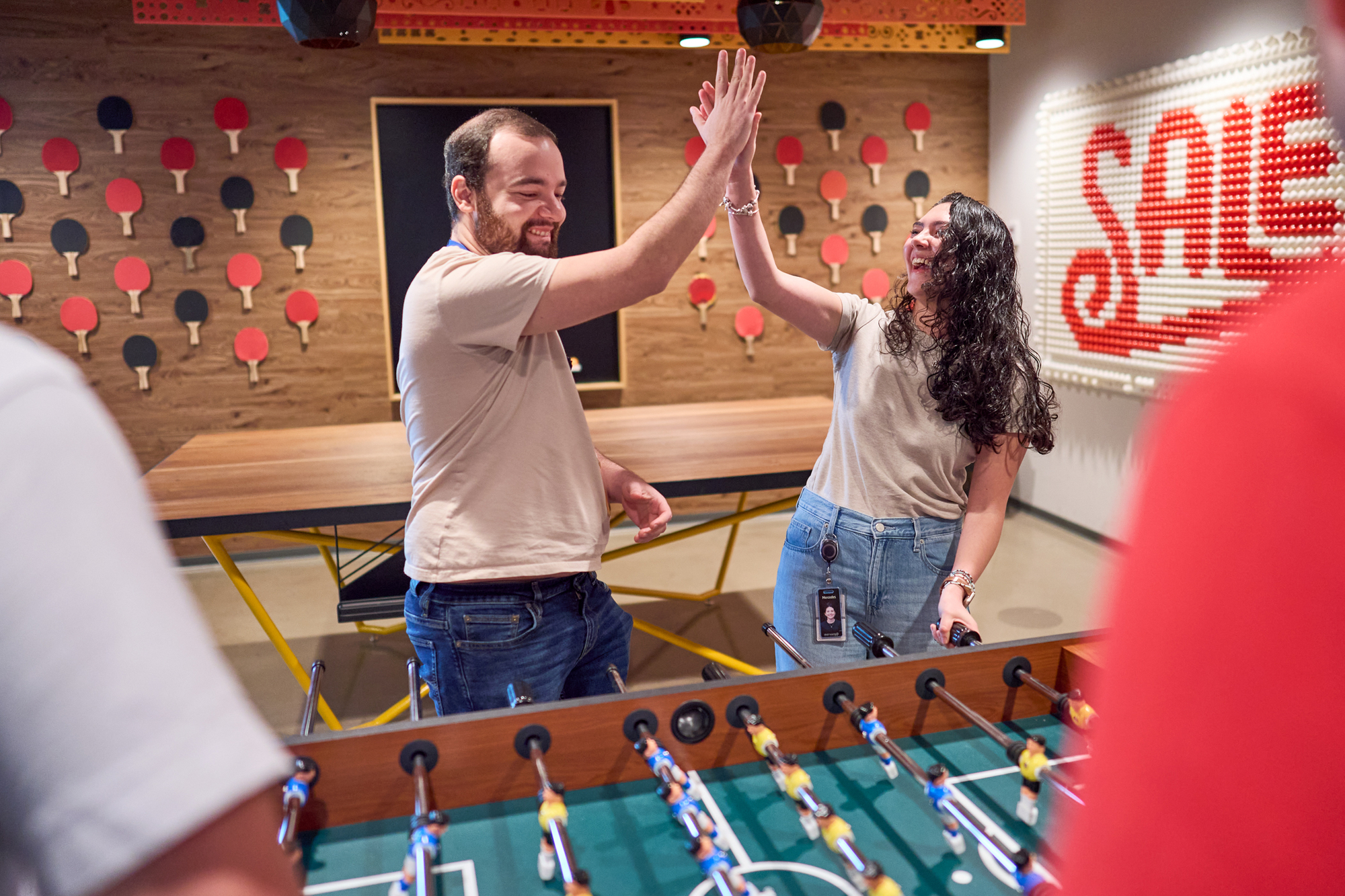 coworkers high five while playing foosball at work 