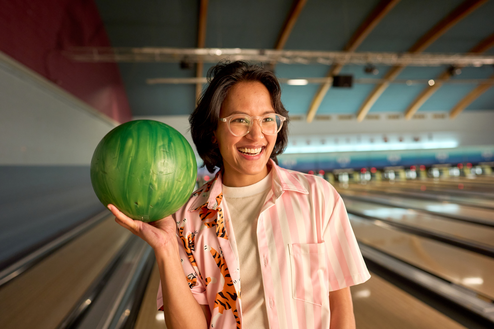 woman holds a bowling ball as she smiles off camera ICCU Premier Visa